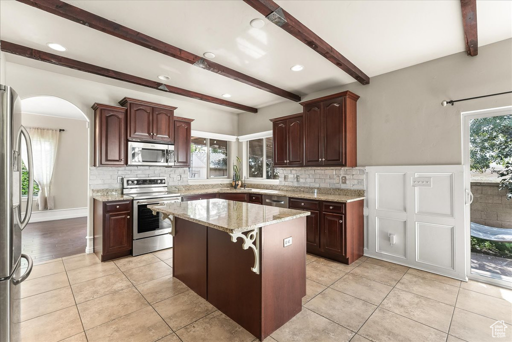 Kitchen with appliances with stainless steel finishes, a center island, sink, and a wealth of natural light
