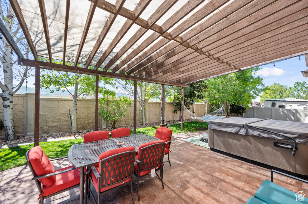 View of patio featuring a pergola, outdoor dining area, a fenced backyard, and a hot tub