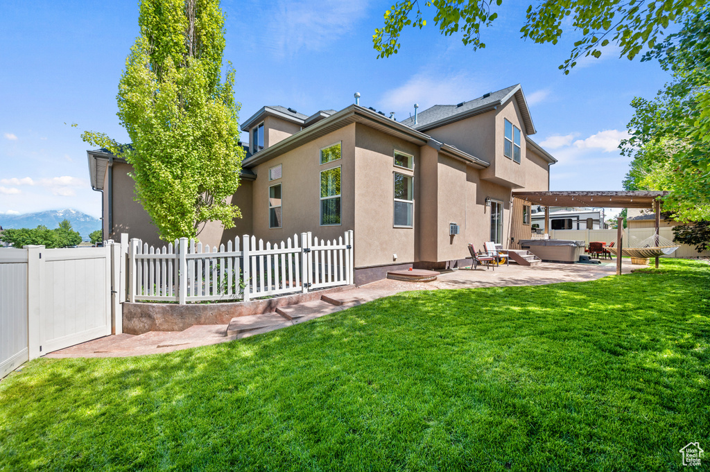 Rear view of house featuring a patio area, stucco siding, fence private yard, and a lawn