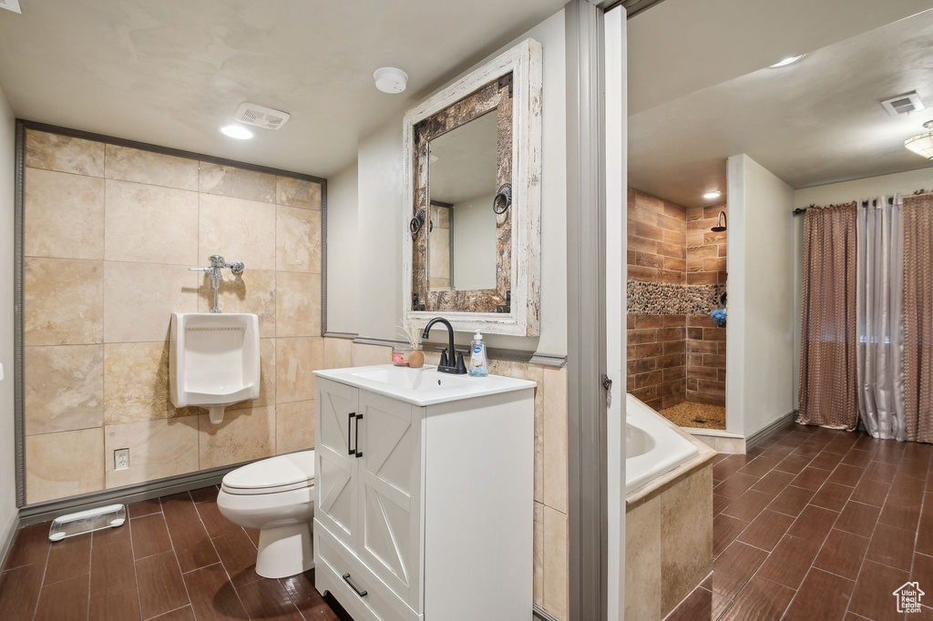 Full bathroom with vanity, toilet, tile walls, and plus walk in shower