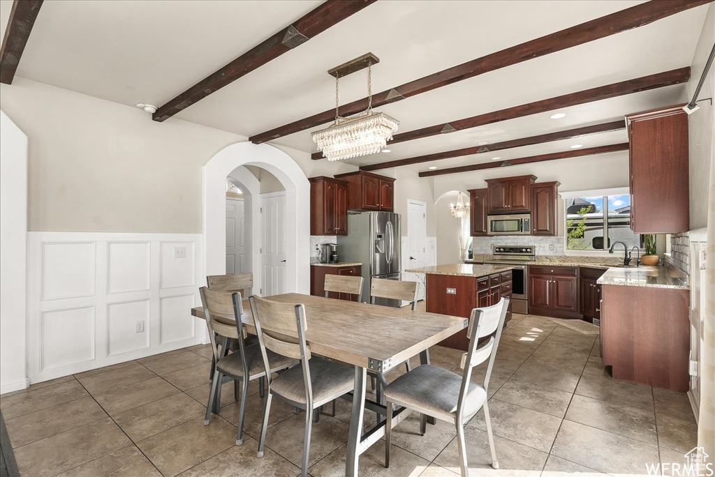 Tiled dining space with an inviting chandelier, sink, and beamed ceiling