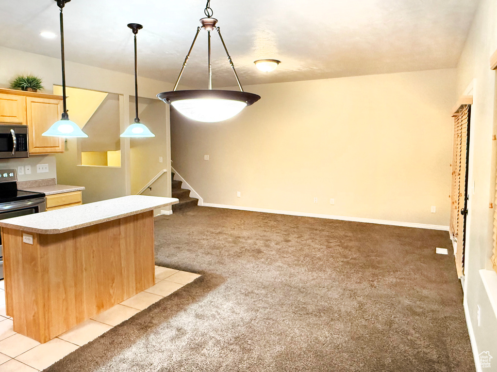 Kitchen with appliances with stainless steel finishes, decorative light fixtures, a kitchen breakfast bar, light colored carpet, and light brown cabinets