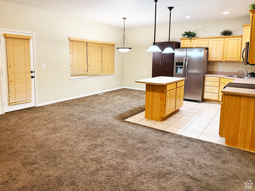 Kitchen with a kitchen island, pendant lighting, sink, stainless steel appliances, and light carpet