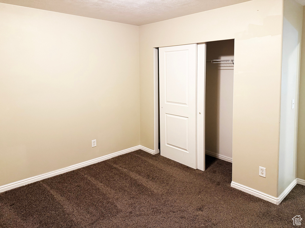 Unfurnished bedroom with dark carpet and a closet