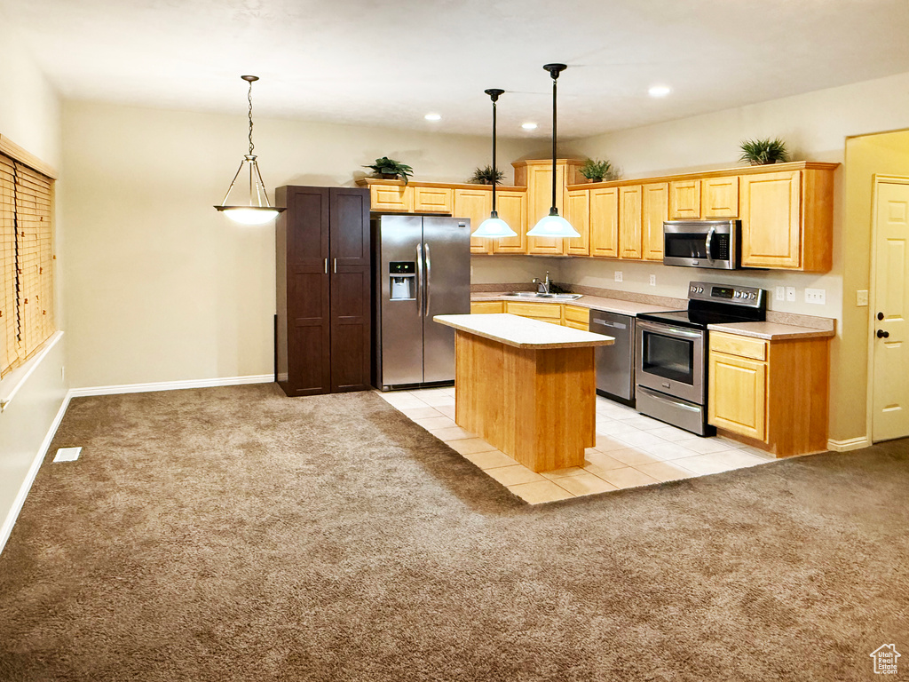 Kitchen with appliances with stainless steel finishes, sink, hanging light fixtures, a center island, and light colored carpet