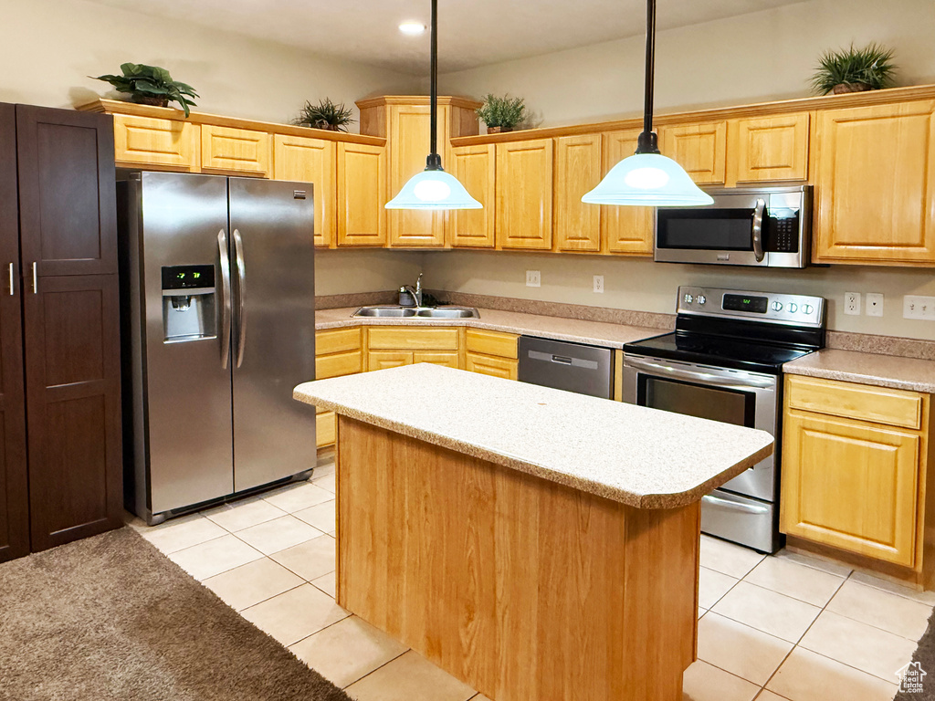 Kitchen featuring light tile patterned floors, sink, hanging light fixtures, stainless steel appliances, and a center island