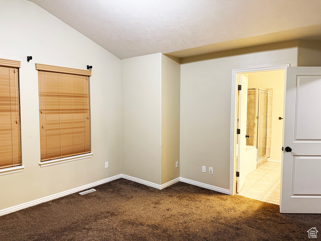 Carpeted spare room featuring lofted ceiling