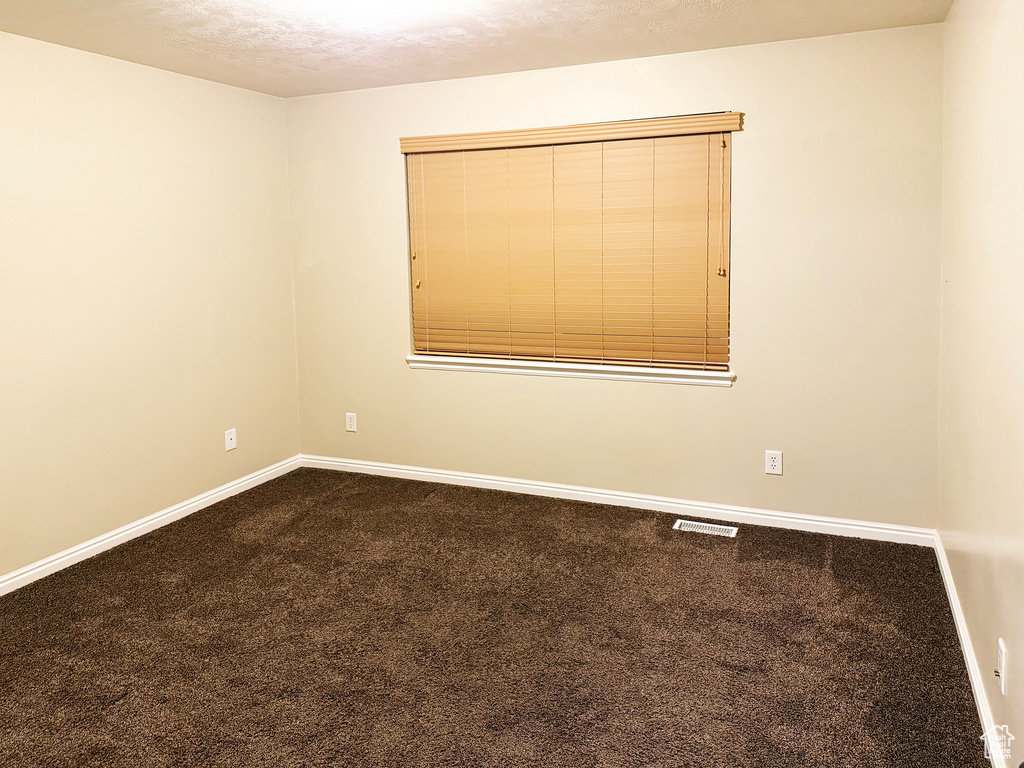 Carpeted spare room featuring a textured ceiling