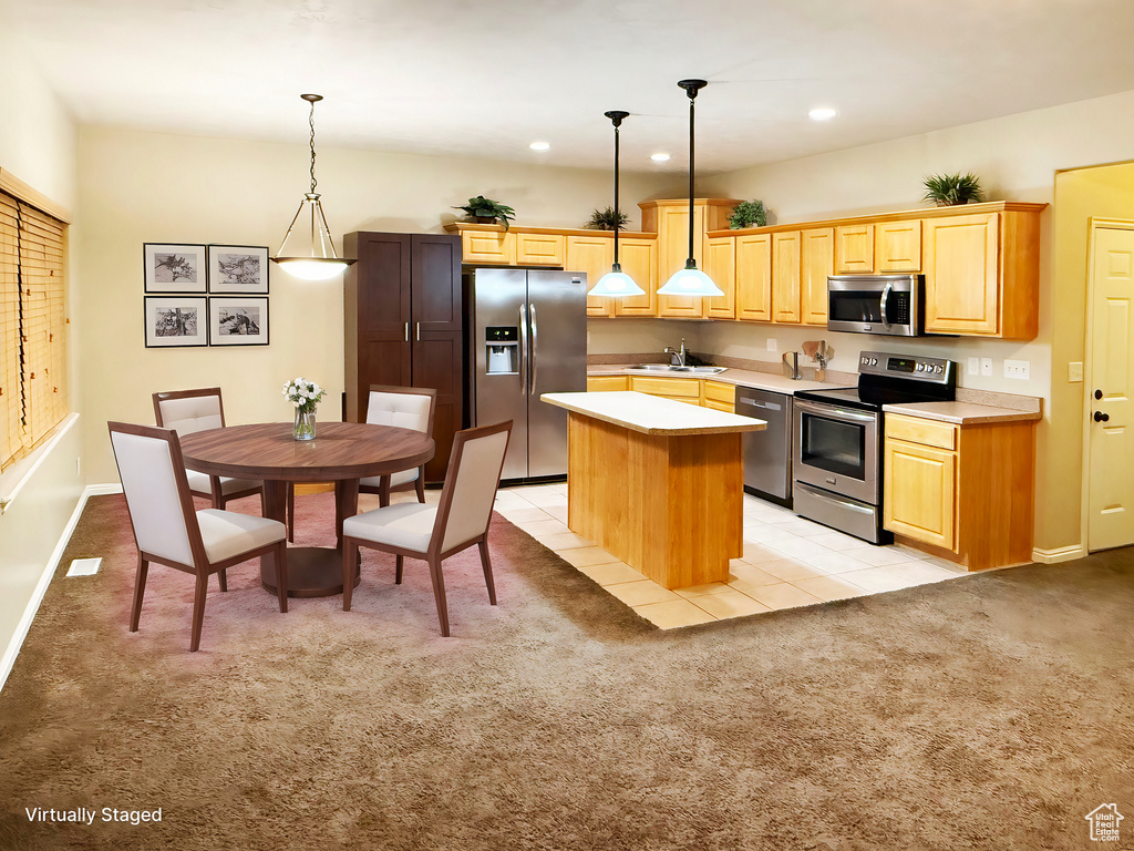 Kitchen with sink, appliances with stainless steel finishes, hanging light fixtures, a kitchen island, and light carpet