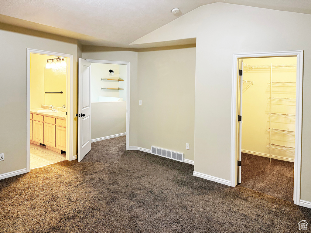 Empty room with lofted ceiling, sink, and carpet