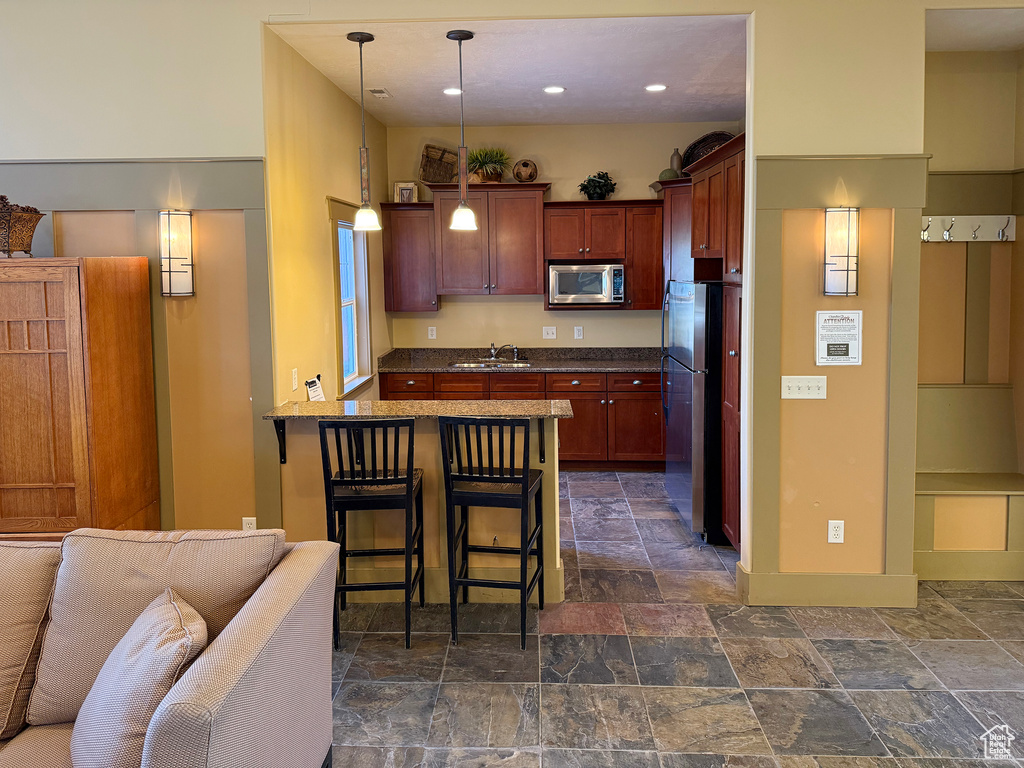 Kitchen with pendant lighting, sink, appliances with stainless steel finishes, a kitchen breakfast bar, and kitchen peninsula