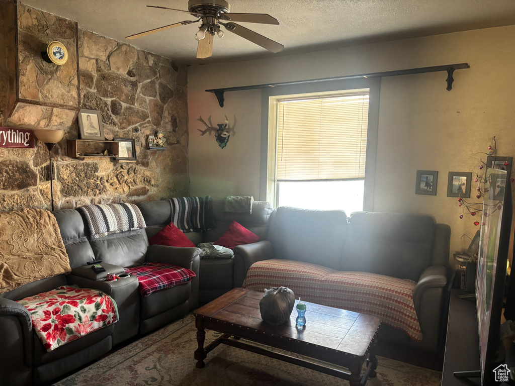 Living room featuring ceiling fan and a textured ceiling