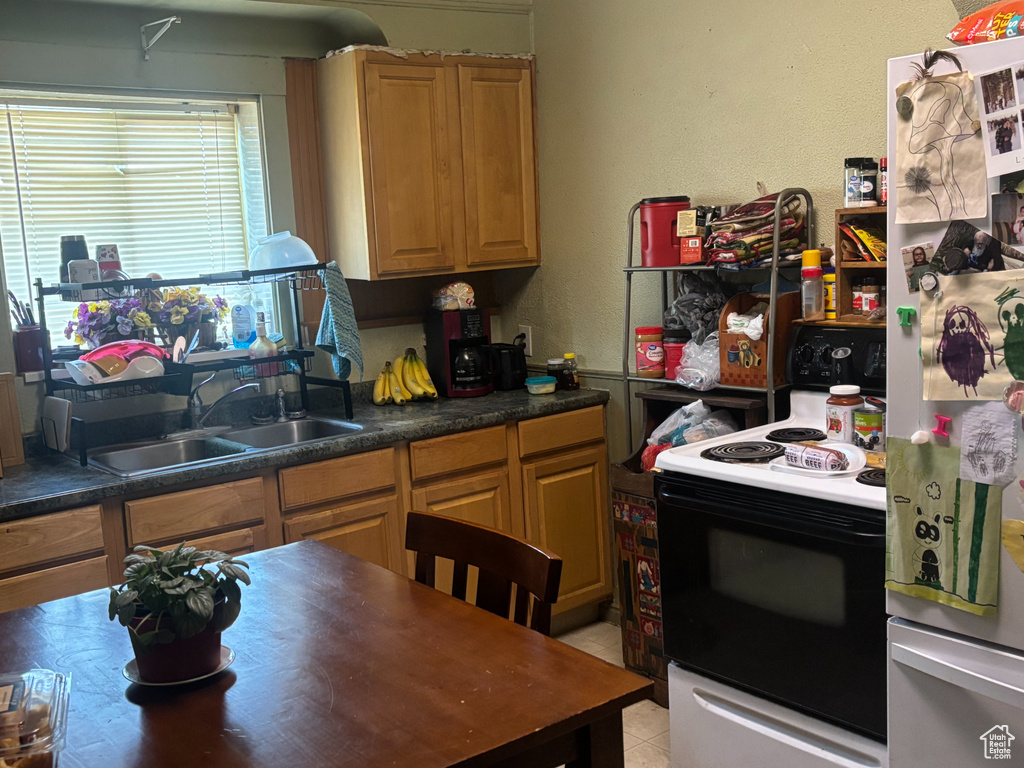 Kitchen with light tile patterned flooring, sink, refrigerator, and electric stove