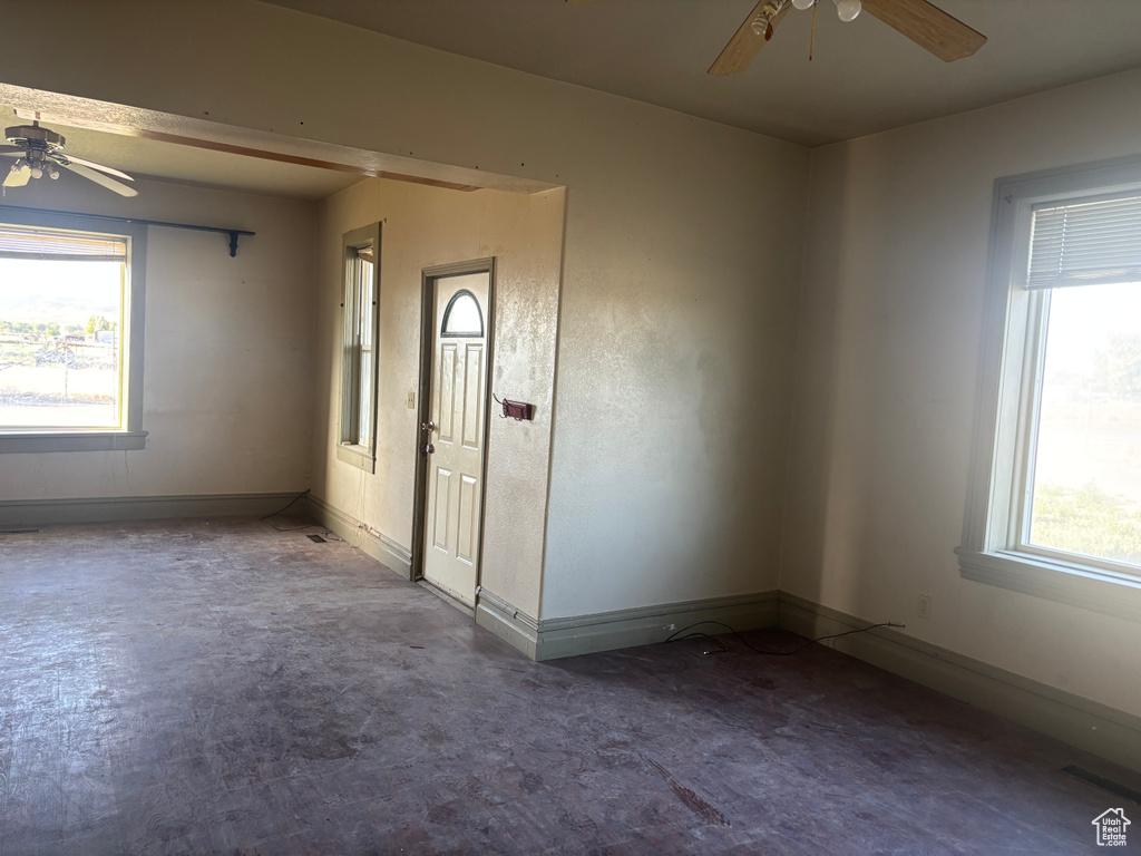 Empty room with ceiling fan, healthy amount of natural light, and baseboards
