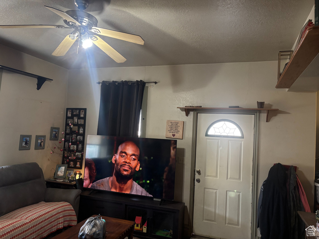 Living room featuring ceiling fan and a textured ceiling