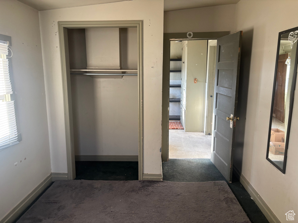 Unfurnished bedroom featuring a closet, carpet floors, and baseboards