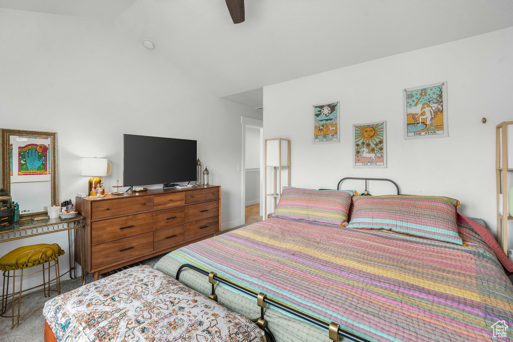 Carpeted bedroom featuring ceiling fan and vaulted ceiling