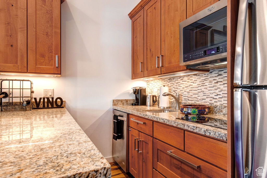 Kitchen featuring tasteful backsplash, sink, light stone countertops, and appliances with stainless steel finishes