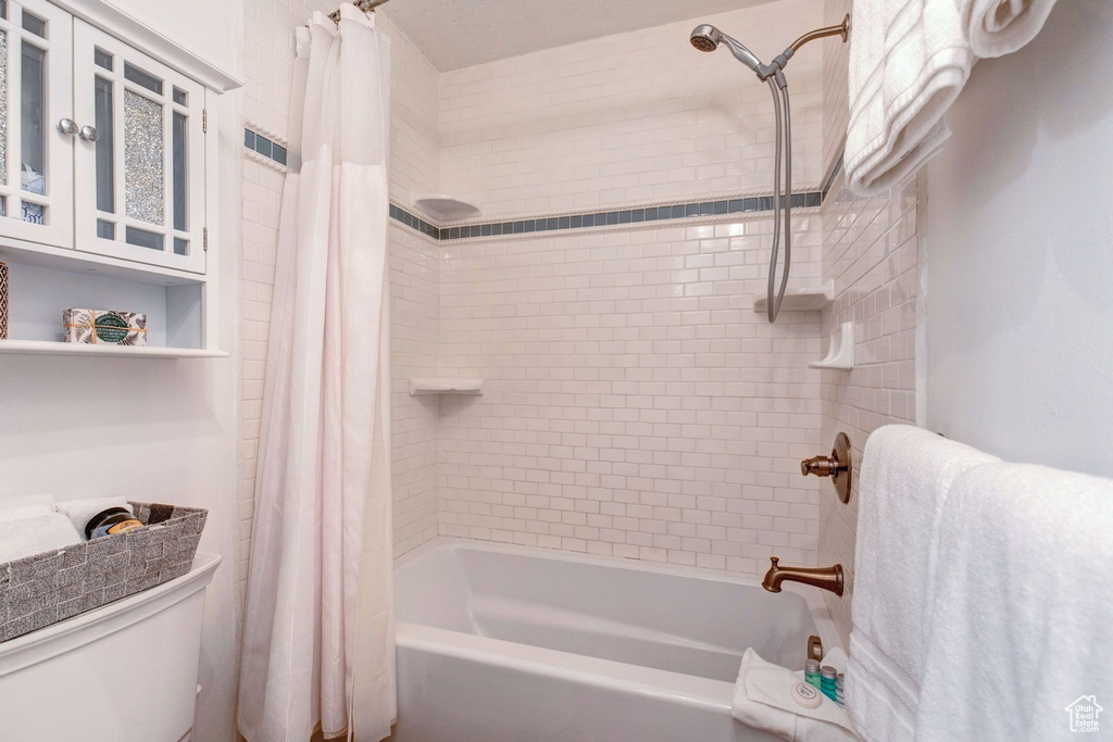 Bathroom featuring toilet and shower / bath combo with shower curtain