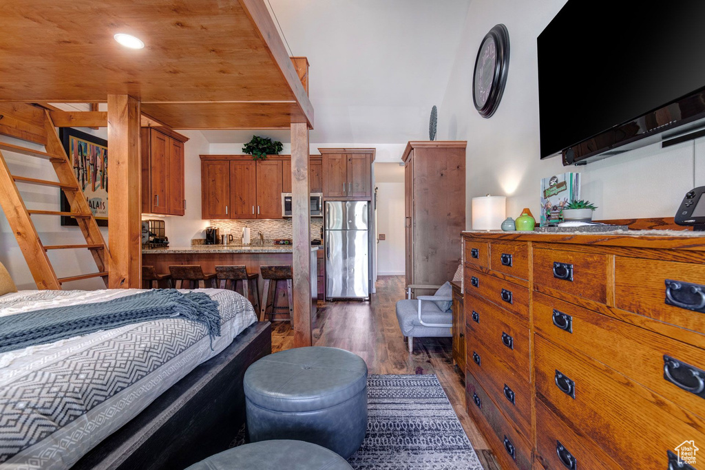 Bedroom featuring dark hardwood / wood-style floors and stainless steel fridge