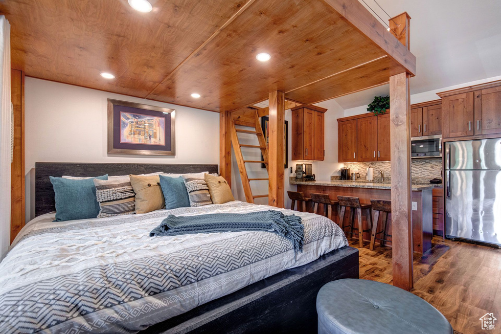 Bedroom with dark hardwood / wood-style flooring, wood ceiling, and stainless steel refrigerator