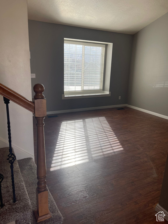 Unfurnished room with dark wood-type flooring and a textured ceiling