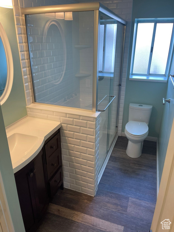 Bathroom with hardwood / wood-style flooring, vanity, toilet, and a shower with shower door