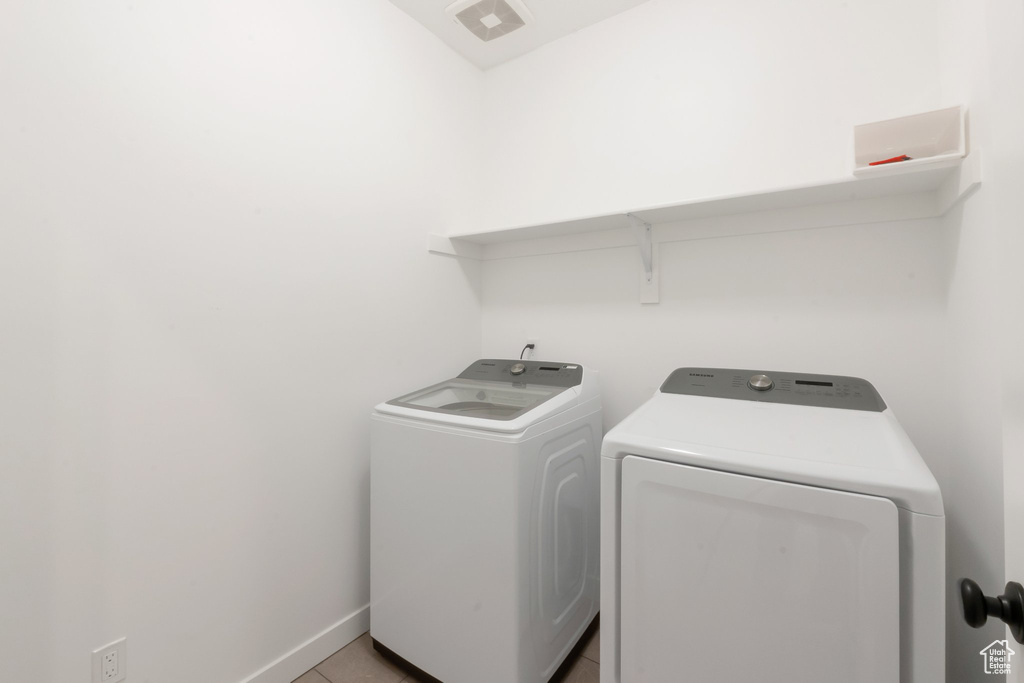 Laundry area with light tile patterned flooring and independent washer and dryer