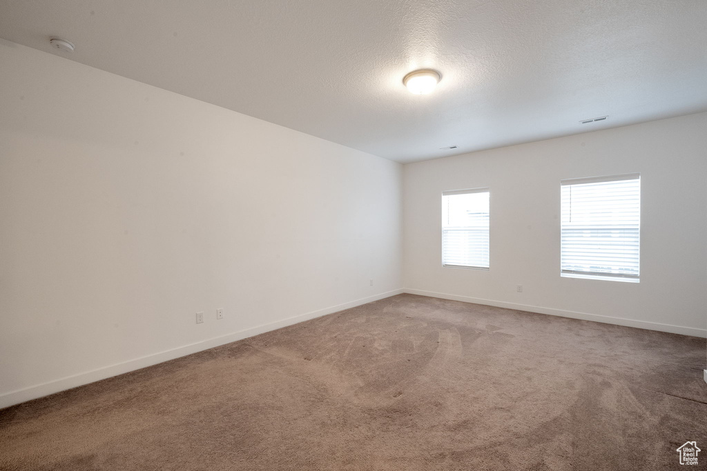 Carpeted spare room featuring a textured ceiling