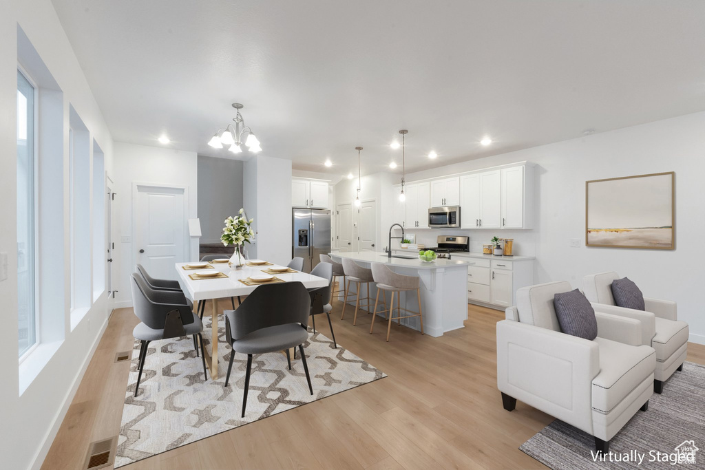 Dining area with sink, an inviting chandelier, and light wood-type flooring