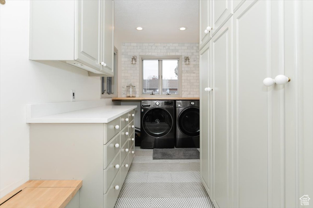 Washroom with separate washer and dryer, cabinets, and light tile patterned flooring