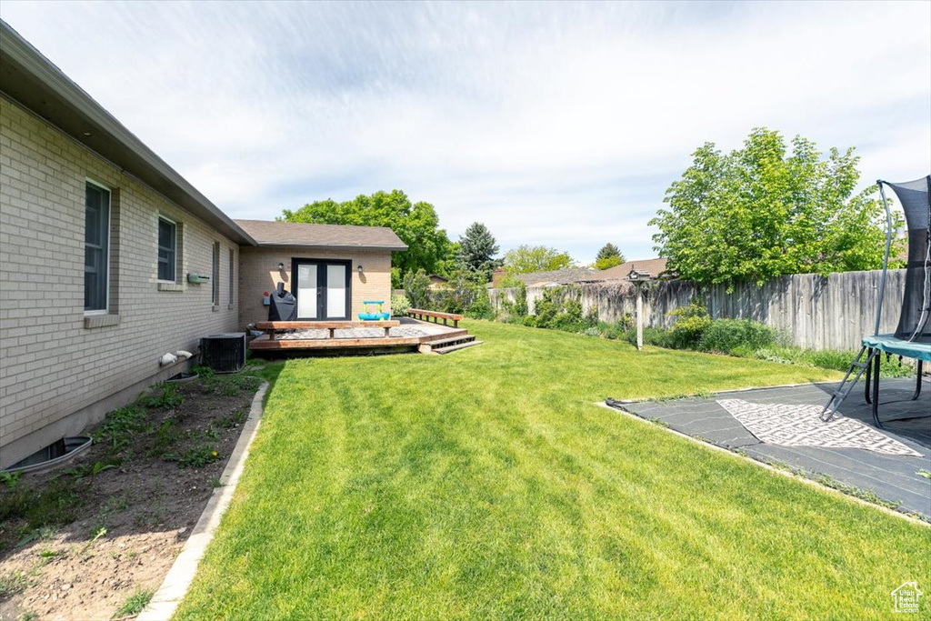 View of yard with a trampoline and a deck
