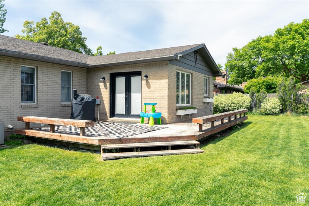 Rear view of house featuring a deck, french doors, brick siding, and roof with shingles