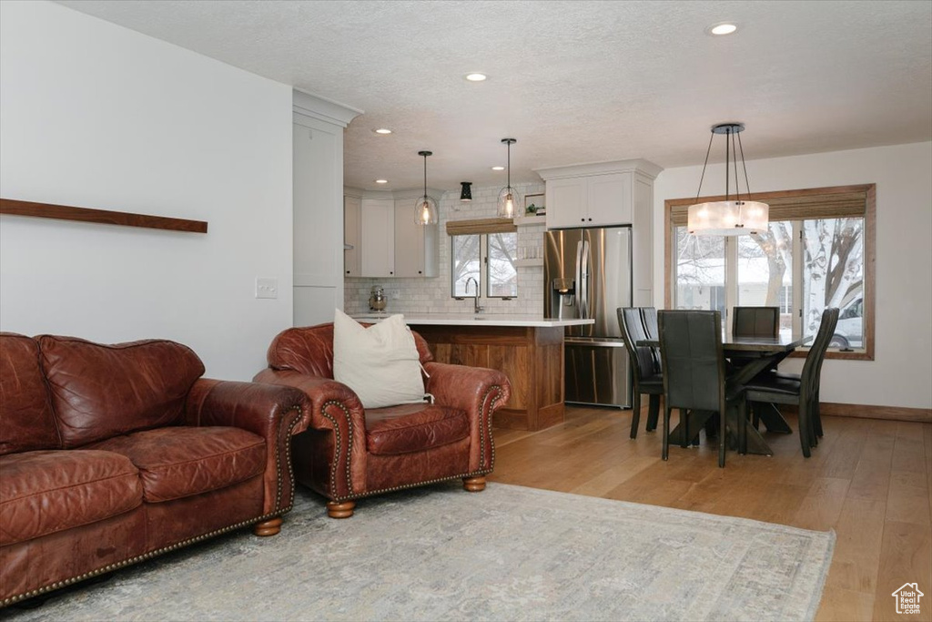 Living room with a notable chandelier, a textured ceiling, and light hardwood / wood-style flooring