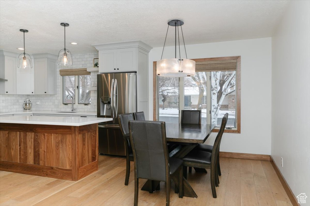 Dining area with sink, a textured ceiling, and light hardwood / wood-style floors