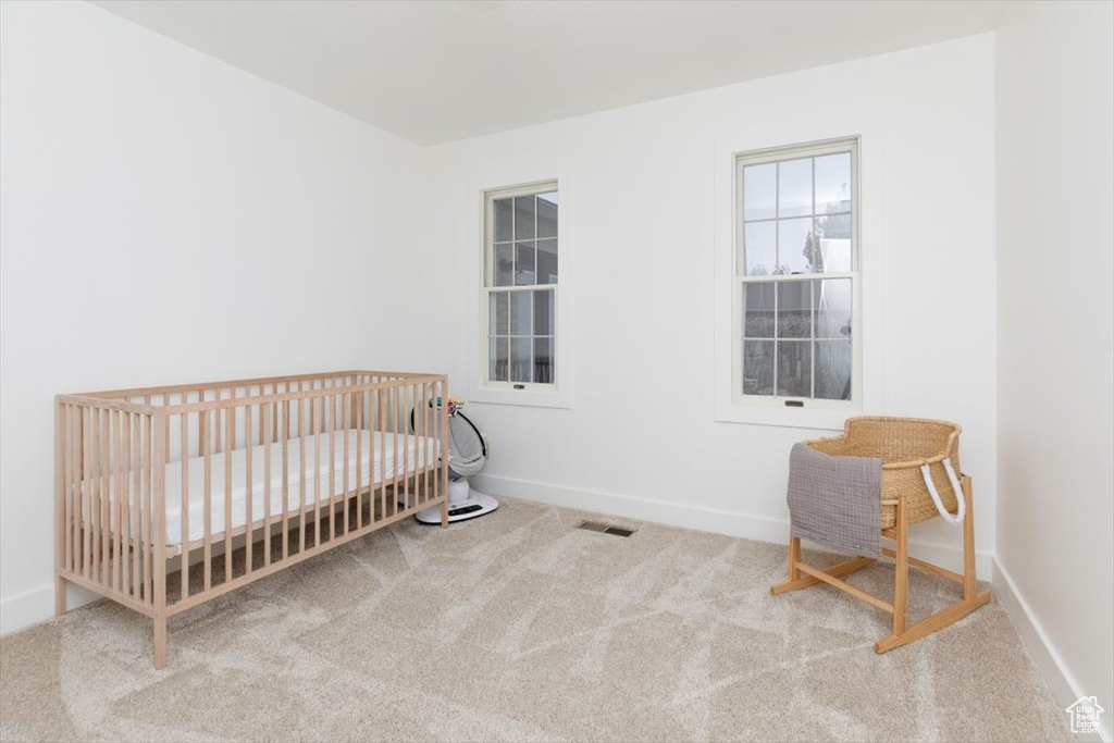 Bedroom featuring a nursery area and carpet flooring