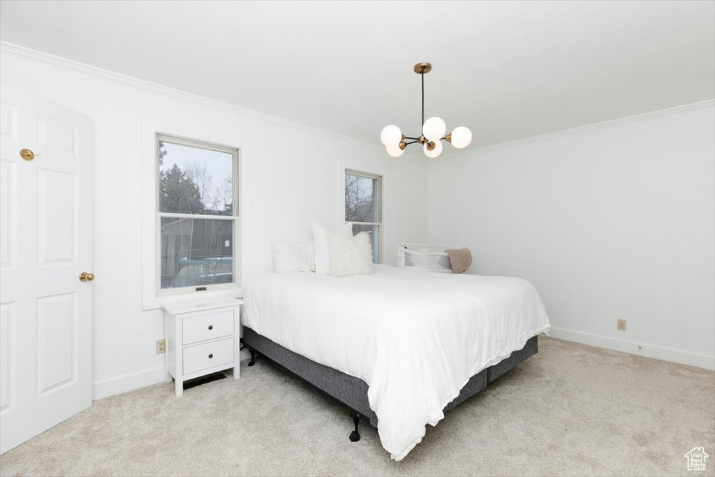 Carpeted bedroom with ornamental molding and a notable chandelier