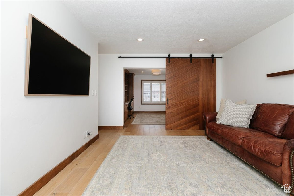 Living room with a barn door, light hardwood / wood-style flooring, and a textured ceiling