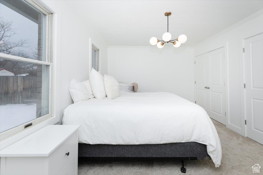 Carpeted bedroom featuring a notable chandelier and crown molding