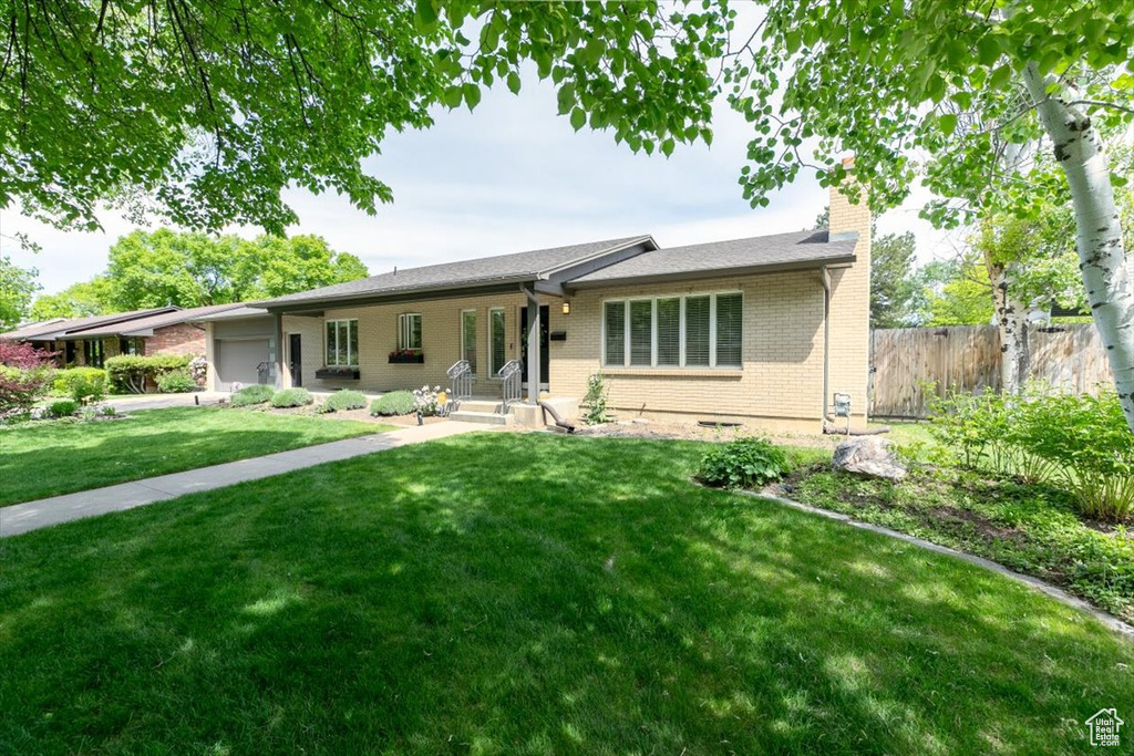 Single story home featuring a chimney, an attached garage, and brick siding