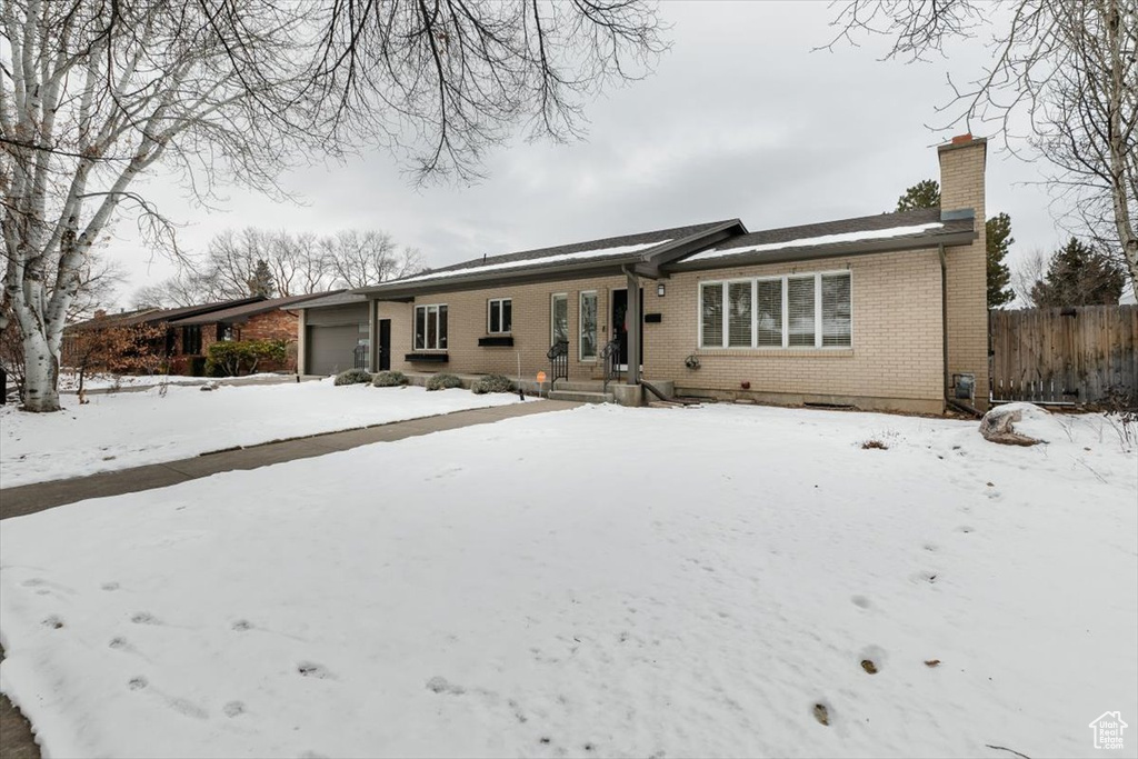 Snow covered house featuring a garage