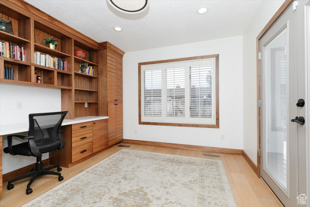 Office featuring built in desk and light hardwood / wood-style flooring