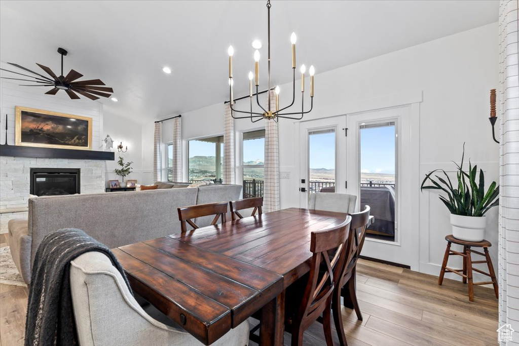 Dining room featuring ceiling fan with notable chandelier, a fireplace, and light hardwood / wood-style floors