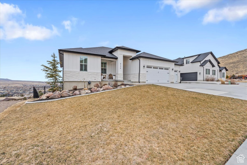 View of front of home with a garage and a front lawn