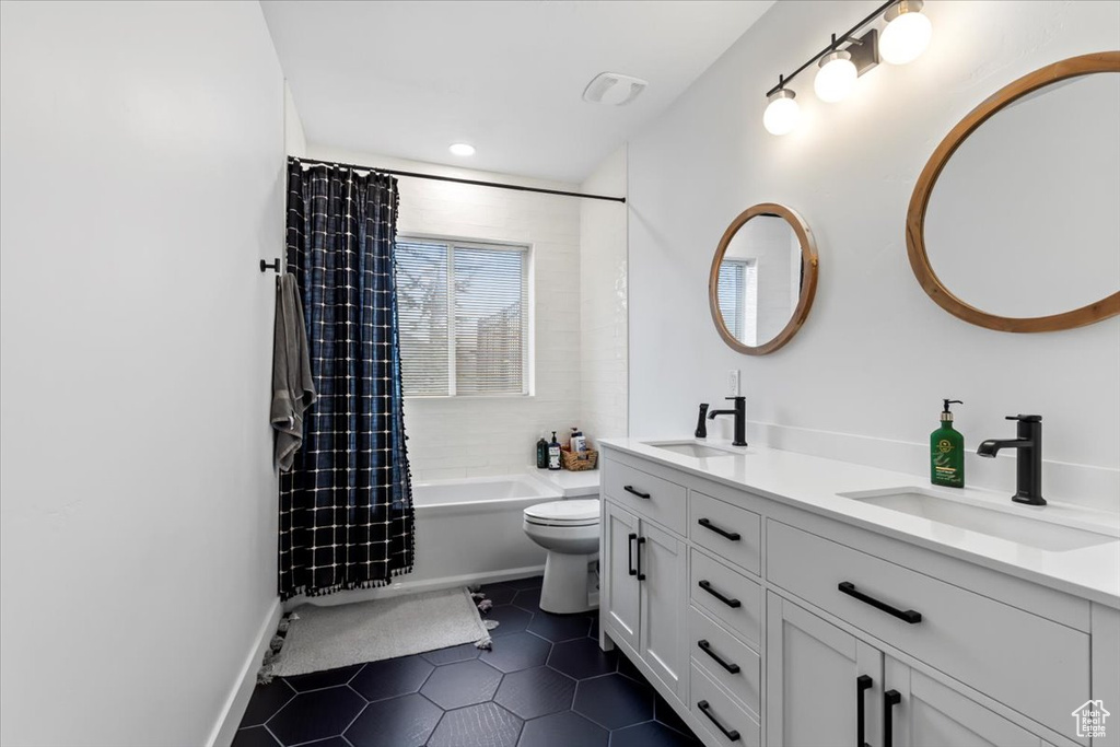 Full bathroom featuring vanity, shower / tub combo with curtain, tile patterned floors, and toilet