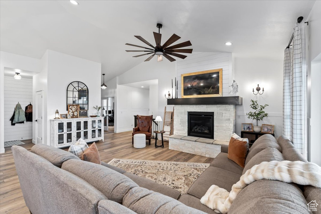 Living room with ceiling fan, lofted ceiling, a fireplace, and light hardwood / wood-style floors