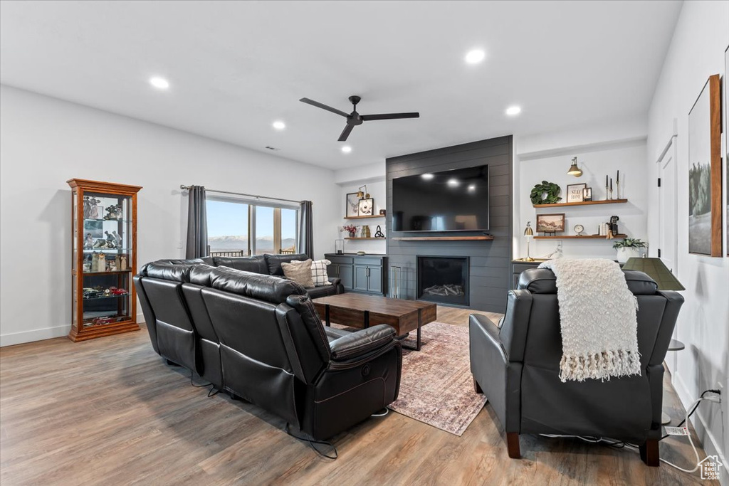 Living room featuring ceiling fan, a fireplace, and hardwood / wood-style floors