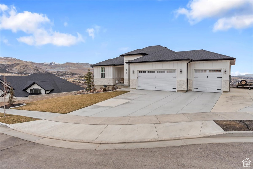 View of front facade with a mountain view, a garage, and a front yard