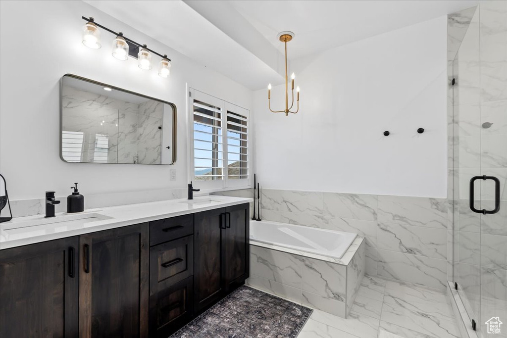 Bathroom with an inviting chandelier, vanity, and separate shower and tub