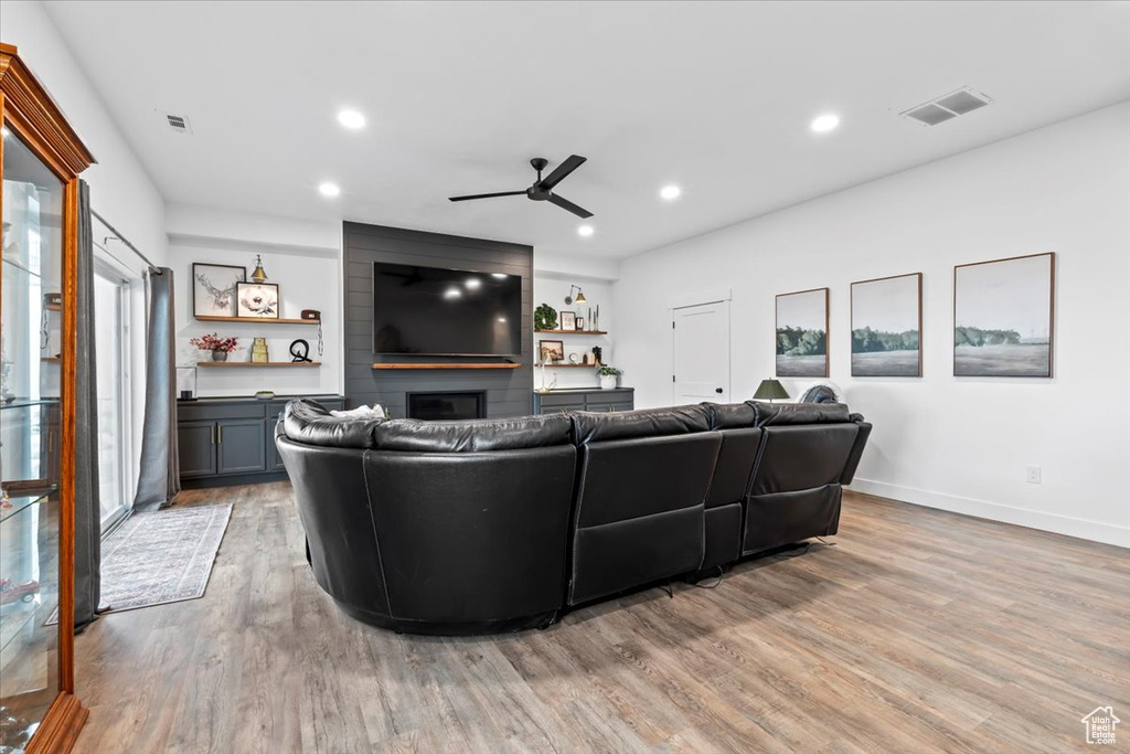 Living room with ceiling fan, a fireplace, and light hardwood / wood-style flooring